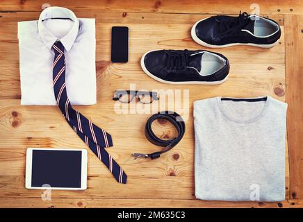 Kit für den modernen Mann. Ein elegantes und legeres Outfit mit digitalen Geräten aus einem hohen Winkel auf einem Holztisch. Stockfoto