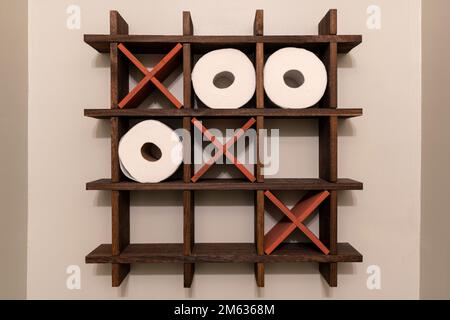 Ein Tic-Tac-Toe-Holzregal für Toilettenpapierrollen. Toilettendekoration. Noughts und Kreuze, XS und OS. Stockfoto