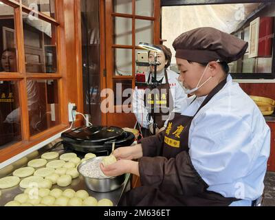 Taiyuan, Chinas Provinz Shanxi. 25. Januar 2022. Arbeiter werben für den Verkauf von Mondkuchen durch Livestreaming in einem Lebensmittelgeschäft in der antiken Stadt Pingyao, Nordchina Provinz Shanxi, am 25. Januar 2022. Kredit: Wang Xuetao/Xinhua/Alamy Live News Stockfoto