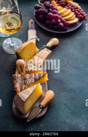 Von oben Käsesorte auf dem Holzschneidbrett, Obstteller und Weingläser Stockfoto