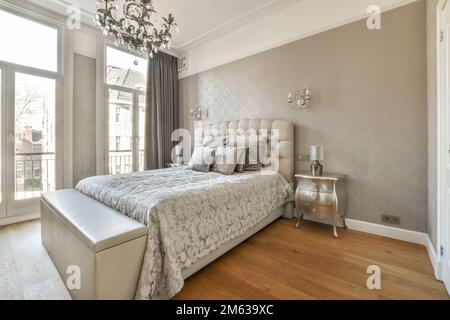 Breites, komfortables Bett mit warmen Decken und weichen Kissen im trendigen Schlafzimmer des modernen Apartments Stockfoto