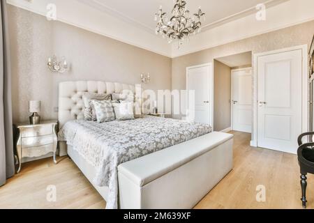 Breites, komfortables Bett mit warmen Decken und weichen Kissen im trendigen Schlafzimmer des modernen Apartments Stockfoto