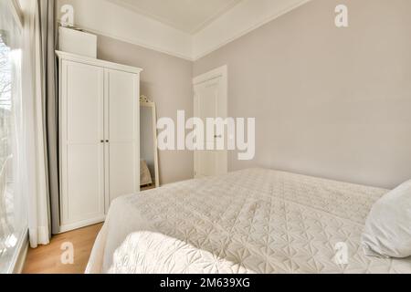 Breites, komfortables Bett mit warmen Decken und weichen Kissen im trendigen Schlafzimmer des modernen Apartments Stockfoto