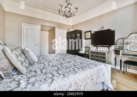 Breites, komfortables Bett mit warmen Decken und weichen Kissen im trendigen Schlafzimmer des modernen Apartments Stockfoto