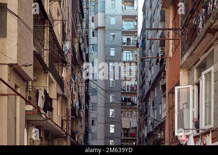 Außenansicht eines Hochhauses mit elektrischen Kabeln und Leinen, die an sonnigen Tagen im Ghetto in Batumi, Georgia, an Seilen trocknen Stockfoto