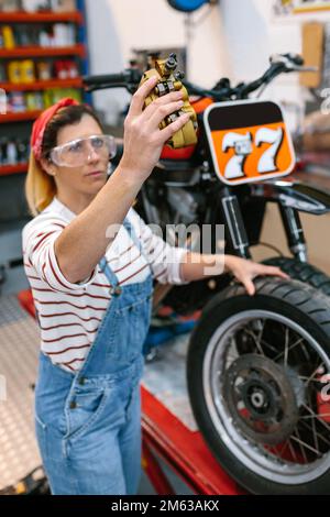 Mechanikerin, die die Bremsanlage des Motorrads im Werk überprüft Stockfoto