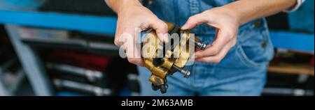 Eine Mechanikerin prüft das Bremssattelsystem in der Garage Stockfoto