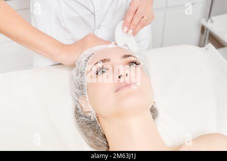 Kosmetologe macht Gesichtsmassage mit Gua Sha Stein der weiblichen Gesichtshaut für Lymphdrainage, Anti-Aging-Hautpflege kosmetische Prozedur im Beauty Spa Stockfoto