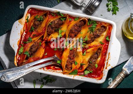 Hausgemachte Pasta-Muscheln, italienische Conchiglioni gefüllt mit Hackfleisch aus Hackfleisch in Tomatensauce mit Kräutern Stockfoto