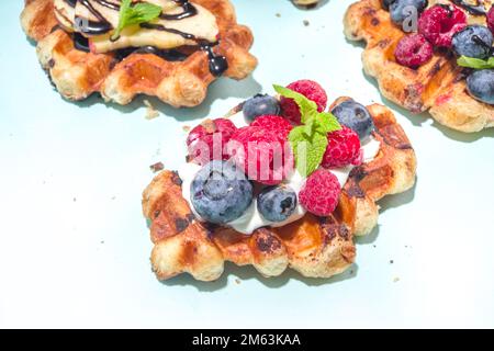 Modernes Dessert-Croffle: Eine Mischung aus Croissants und Waffeln, Waffeleisen-Pfanne mit Waffeleisen, Beerenfrüchten und Schokolade Stockfoto