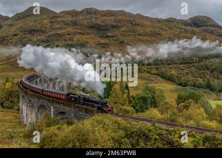 Die Glenfinnan-Dampfeisenbahn überquert die berühmte Brücke im schottischen Hochland, das von Harry Potter und dem Hogwarts Express genutzt wird. Stockfoto