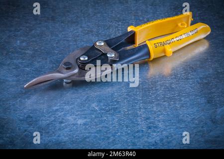 Blechschere aus Stahl auf zerkratztem metallischem Hintergrund, Nahaufnahme des Baukonzepts. Stockfoto