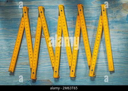 Gelbe Holzuhr auf altem Holzbrett direkt über dem Baukonzept. Stockfoto