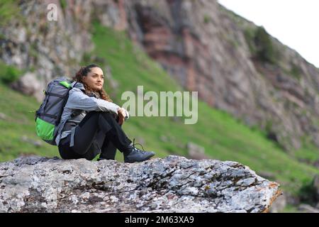 Hikker sitzt auf einem Felsen und denkt über die Aussicht auf den Berg nach Stockfoto