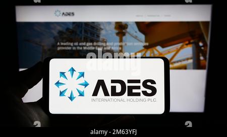 Person, die ein Smartphone mit dem Logo des ägyptischen Unternehmens ADES International Holding auf dem Bildschirm vor der Website hält. Konzentrieren Sie sich auf das Display des Telefons. Stockfoto