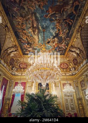 Wunderschön eingerichtete Napoleon Apartments im Louvre Palace. Königliche Familienzimmer mit kardinalroten Vorhängen, goldverzierten Wänden, Gemälden und Kristalltafel Stockfoto