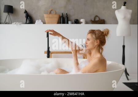 Junge Frau, die im Badezimmer mit Schaumstoffblasen badet Stockfoto