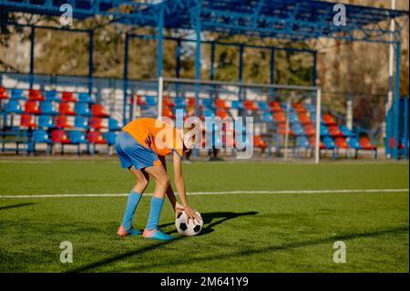 Der Junior-Fußballspieler legt den Ball für Freistoß oder Elfmeter auf den Rasen Stockfoto