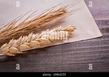 Weizen- und Roggenohren auf altem Papier, alte Holzbretter, Speisen- und Getränkekonzept Stockfoto