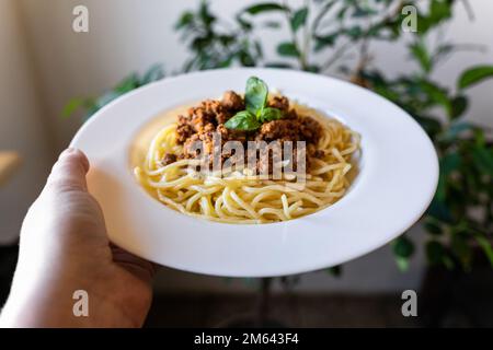Teller mit klassischer italienischer Spaghetti Bolognese in der Hand. Stockfoto