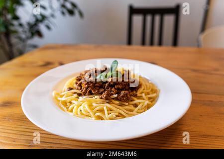 Teller mit traditioneller italienischer Spaghetti Bolognese auf einem Holztisch im Restaurant Stockfoto