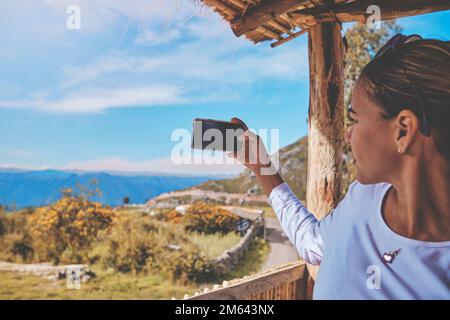 Frau genießt wunderschönen Sonnenuntergang, während sie in den Bergen mit Hütten und Hügeln reist. Stockfoto