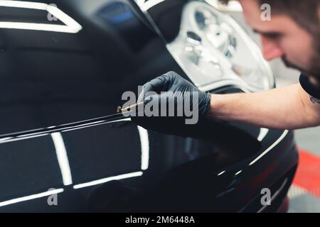 Professionelle Autoverbesserung durch einen Experten für ein schwarzes Luxusfahrzeug. Fahrzeugdetails. Hochwertiges Foto Stockfoto