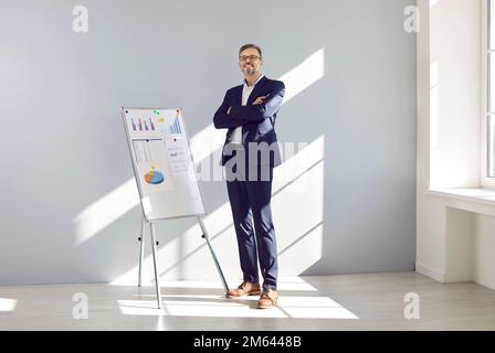 Porträt eines glücklichen, ausgereiften Vertriebsleiters, der vor einem Whiteboard im Büro steht Stockfoto