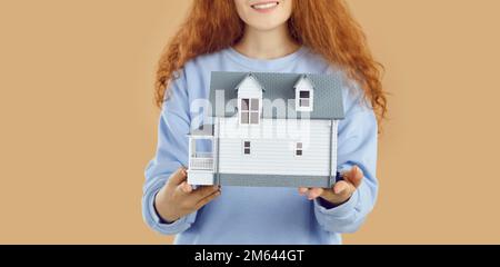 Kleines Modell eines modernen und stilvollen zweistöckigen Wohngebäudes in weiblichen Händen. Stockfoto