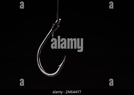 Angelhaken auf schwarzem Hintergrund. Falle, fangen, riskieren. Idee eines Geschäftskonzepts. Stockfoto