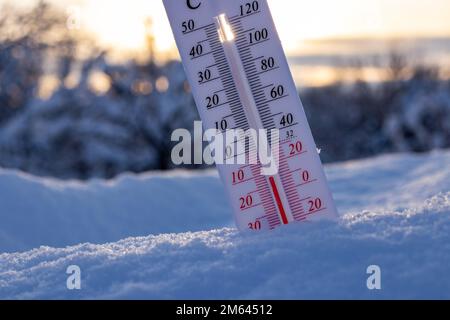 Das Thermometer auf Schnee zeigt niedrige Temperaturen in celsius oder Farenheit an. Bei Sonnenuntergang. Stockfoto