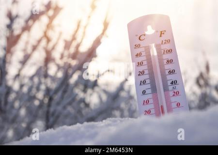 Das Thermometer liegt im Winter auf dem Schnee und zeigt eine negative Temperatur. Meteorologische Bedingungen in einem rauen Klima im Winter mit niedriger Luft und amb Stockfoto