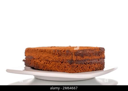 Ein Stück Trüffelkuchen auf einer weißen Keramikuntertasse, Makroaufnahme auf weißem Hintergrund. Stockfoto