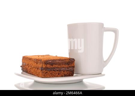 Ein Stück Trüffelkuchen auf einer weißen Keramikuntertasse und einer Tasse, Makroaufnahme auf weißem Hintergrund. Stockfoto