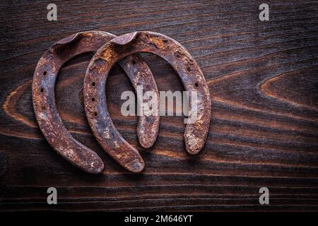 Verrostetes, dreckiges Hufohr auf altem dunklem Holzbrettbaukonzept. Stockfoto
