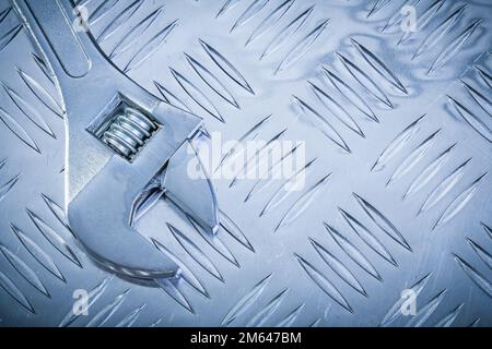 Verstellbarer Edelstahlschlüssel auf gerillter Metallplatte Kopierraum Baukonzept. Stockfoto