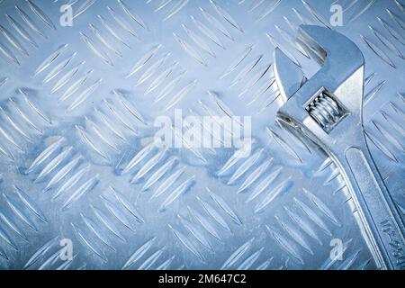 Verstellbarer Edelstahlschlüssel auf gerilltem Metallblech Baukonzept. Stockfoto