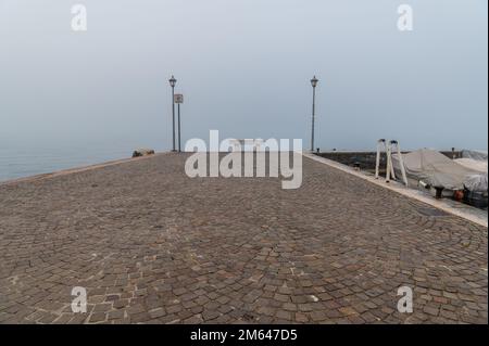 Alter Hafen der kleinen und malerischen Stadt Lazise am Gardasee in der Wintersaison. Lazise, Provinz Verona, Norditalien - Europa Stockfoto