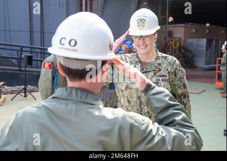 NEWPORT NEWS, VA (30. März 2022) USA Lieutenant Marisa St. Clair, dem Flugzeugträger Pre-Commissioning Unit (PCU) John F. Kennedy (CVN 79) zugeteilt, erhält während einer Abschiedsfeier an Bord des Schiffes einen Abschiedsgruß von Captain Todd Marzano, kommandierender Offizier. Kennedy ist der zweite Flugzeugträger der Ford-Klasse und befindet sich in der Huntington Ingalls Industries Newport News Shipyard im Bau. Stockfoto