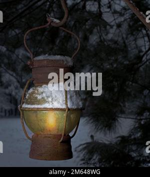 Alte matte Lanter, die nachts in einem verschneiten Baum hängt Stockfoto