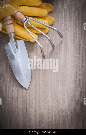 Handschaufel aus Stahl Rechen Leder Sicherheitshandschuhe auf Holzbrettern Landwirtschaftskonzept. Stockfoto