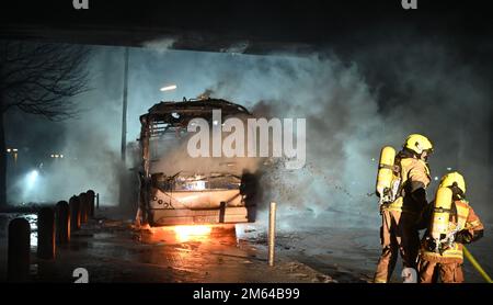 Berlin, Deutschland. 01. Januar 2023. Feuerwehrleute löschen eine Kutsche, die von Unbekannten in Brand gesetzt wurde. Kredit: Paul Zinken/dpa/Alamy Live News Stockfoto