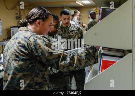 220331-N-CM110-1025 PAZIFIK (31. März 2022) – Marines der Marine Aircraft Group 13 (MAG13) zugewiesen, mit Sitz in Yuma, Arizona, halten Sie Ausschau nach Büchern, die Sie an Bord des Amphibienschiffs USS Tripoli (LHA 7), 31. März, lesen können. Tripoli führt gerade Routineeinsätze in der US-3.-Flotte durch. Stockfoto