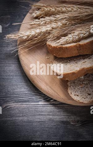 Brotscheiben auf Holzschnitzerbrett, goldene Weizenrohrohren, Draufsicht. Stockfoto