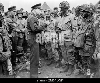 General Dwight D. Eisenhower spricht vor dem D-Day gegen amerikanische Fallschirmjäger. General Dwight D. Eisenhower gibt den Tagesbefehl. "Voller Sieg - nichts Geringeres" an Fallschirmjäger in England, kurz bevor sie an Bord ihrer Flugzeuge gehen, um an dem ersten Angriff auf die Invasion des europäischen Kontinents teilzunehmen." Eisenhower trifft sich mit US Co E, 502. Parachute Infanterie Regiment (Strike) der 101. Airborne Division, Foto am Greenham Common Airfield in England, ca. 8:30 Uhr am 5. Juni 1944. USA Militärfoto. Stockfoto