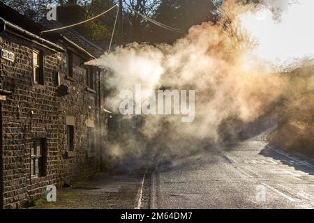 Limbrick, Lancashire. Wetter in Großbritannien. -3 °C im Nordwesten, da die frühe Morgensonne die Wärmedampfemissionen von Wohngrundstücken in Long Lane deutlich macht. Kessel erzeugen lange Dampffahnen, wobei die Luftfeuchtigkeit ebenfalls eine wichtige Rolle bei den Kondensationsprozessen spielt. Rauchgase kommen in Kontakt mit der kalten, feuchten Luft und beginnen dann mit der Erzeugung langer Wasserfahnen winziger Wassertropfen. Kredit: MediaWorldImages/AlamyLiveNews Stockfoto