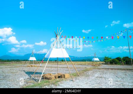 Bunte kleine Flaggen am Himmel. Winkende kleine bunte Flaggen, die am Seil hängen, um Urlaub vor blauem Himmel zu machen. Stockfoto