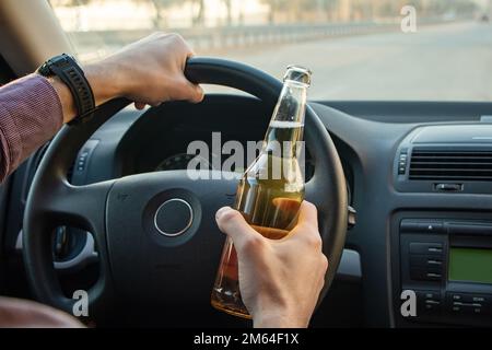 Ein Mann, der Bier trinkt, während er Auto fährt. Das Konzept "nicht trinken und fahren" Stockfoto