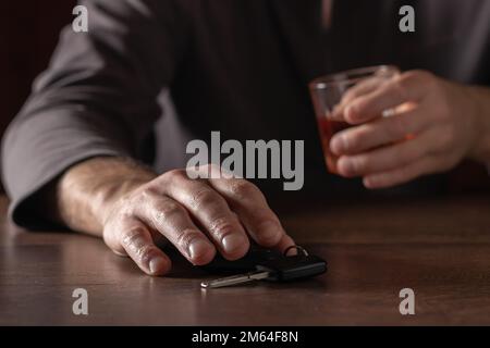 Nicht trinken und Auto fahren. Betrunkener Mann mit Glasalkohol in der Hand, der Autoschlüssel nimmt. Stockfoto