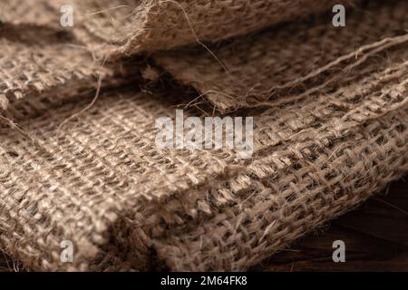 Die ländliche Beschaffenheit des Sacktuchs. Hintergrund aus sehr groben, groben Geweben aus Flachs, Jute oder Hanf. Leinenbeutelmaterial. Konstruktionselement. Abfeuern und Stockfoto